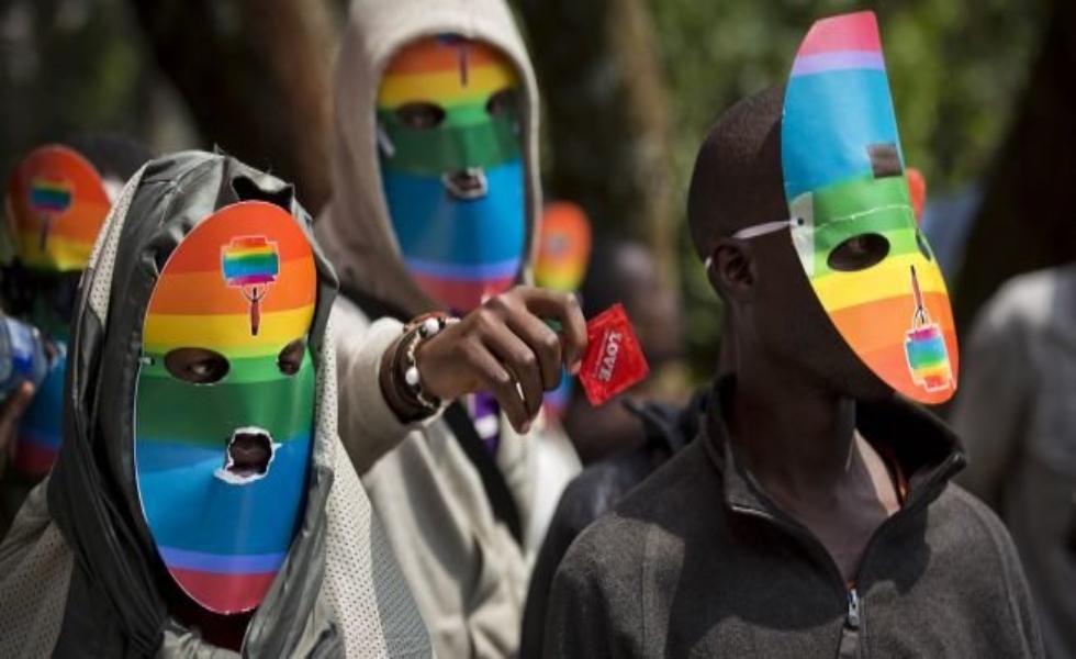 FILE - In this Monday, Feb. 10, 2014 file photo, Kenyan gays and lesbians and others supporting their cause wear masks to preserve their anonymity and one holds out a condom, as they stage a rare protest, against Uganda's increasingly tough stance against homosexuality and in solidarity with their counterparts there, outside the Uganda High Commission in Nairobi, Kenya. Uganda's president Yoweri Museveni is expected to sign Monday, Feb. 24, 2014 a controversial anti-gay bill that allows harsh penalties for homosexual offenses, a bill which rights groups have condemned as draconian in a country where homosexuality is already illegal. (AP Photo/Ben Curtis, File)