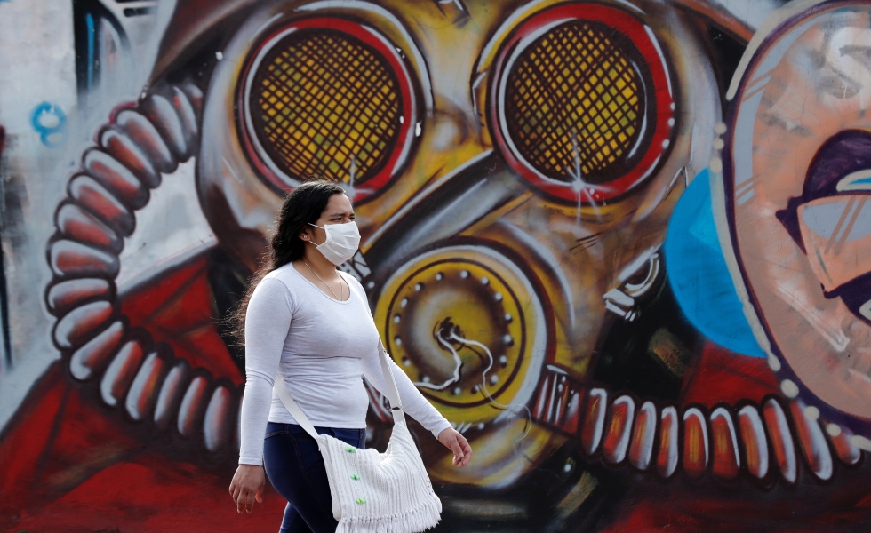 Una mujer con tapabocas camina el pasado jueves 2 de julio del 2020 frente a un grafiti en Bogot· (Colombia). EFE/ Mauricio DueÒas CastaÒeda