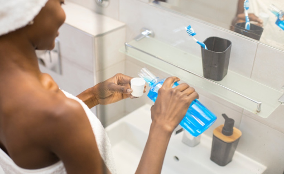 Young woman washing her teeth with mouthwash. Unrecognizable African female
