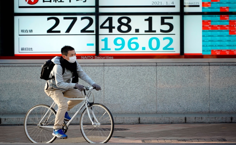 Tokyo (Japan), 04/01/2021.- A passerby cycles past a stock market indicator in Tokyo, Japan, 04 January 2021. The 225-issue Nikkei Stock Average closed the year's first day of trading down after Japan's Prime Minister Yoshihide Suga said the government is considering to declare a state of emergency for Tokyo and surrounding prefectures following the coronavirus surge. (JapÛn, Tokio) EFE/EPA/FRANCK ROBICHON